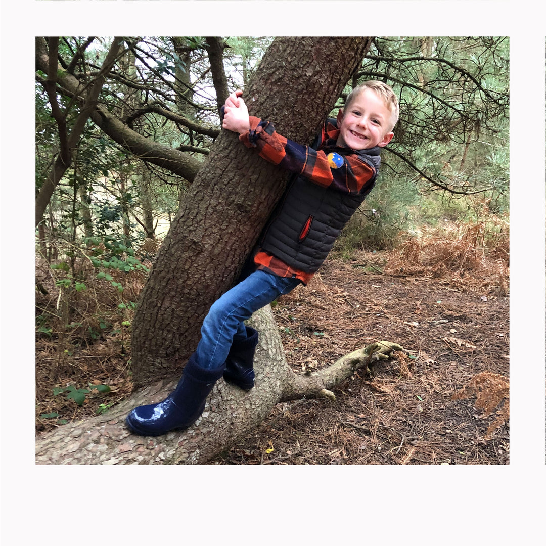 boy hanging from tree wearing welly boots